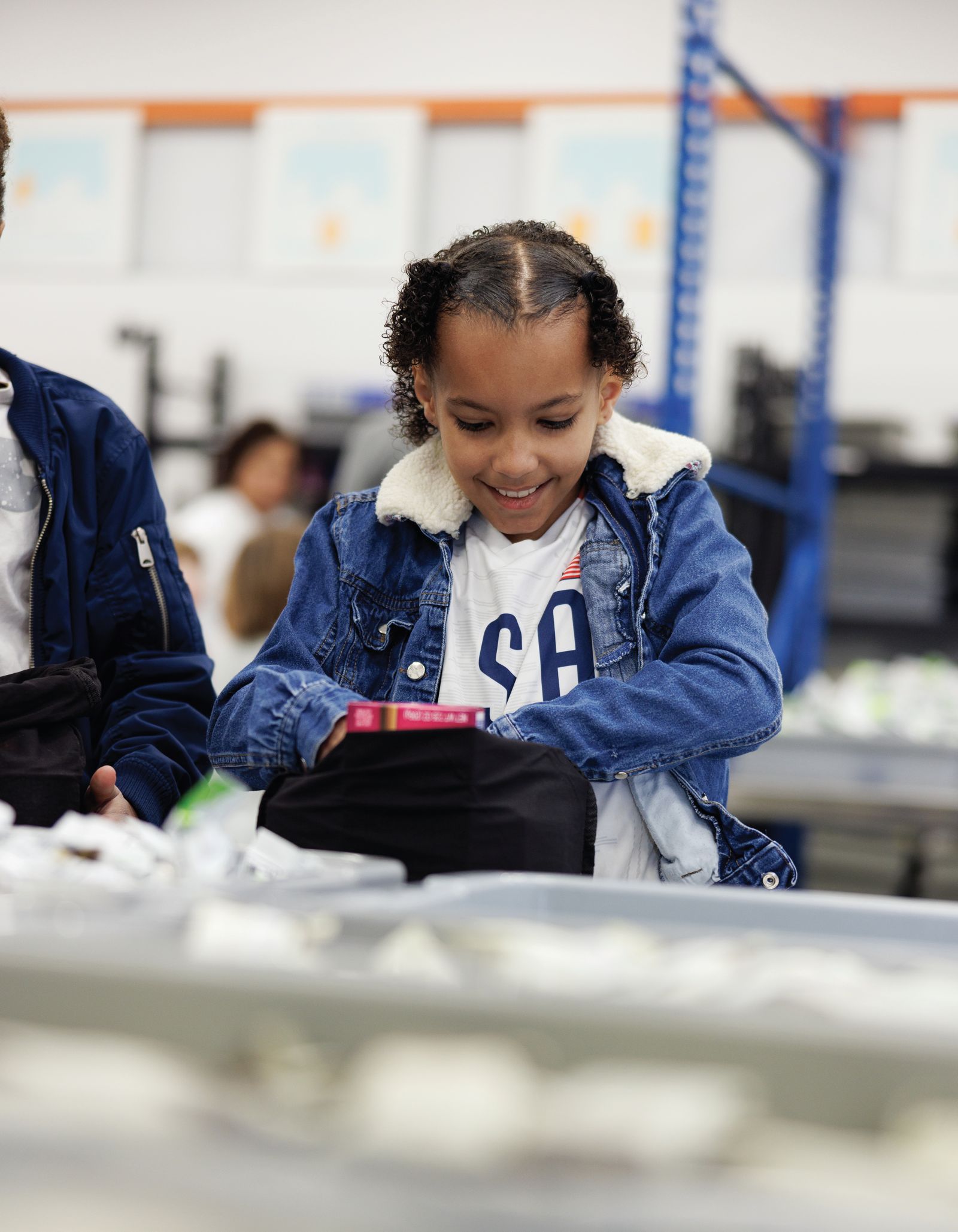 A girl smiles as she packs a USANA Kids Eat bag