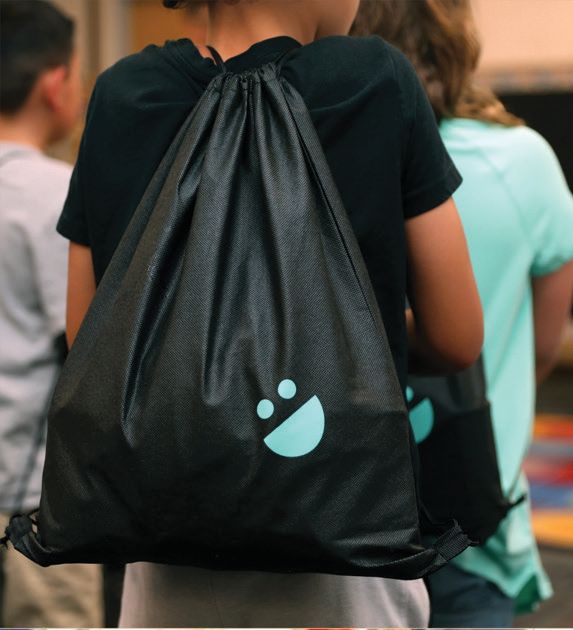 A student wears a USANA Kids Eat drawstring backpack