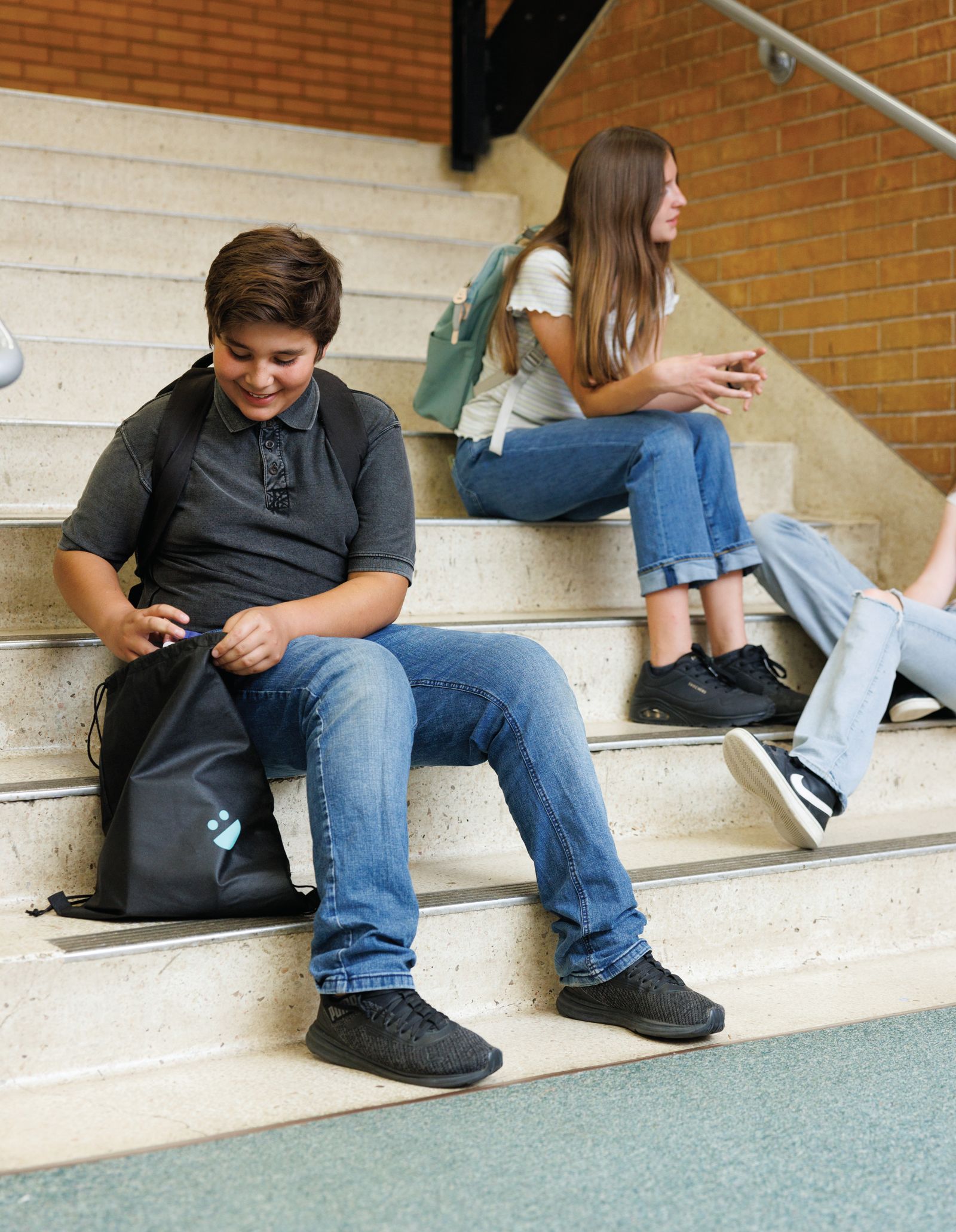 Students on school steps, one with a USANA Kids Eat backpack