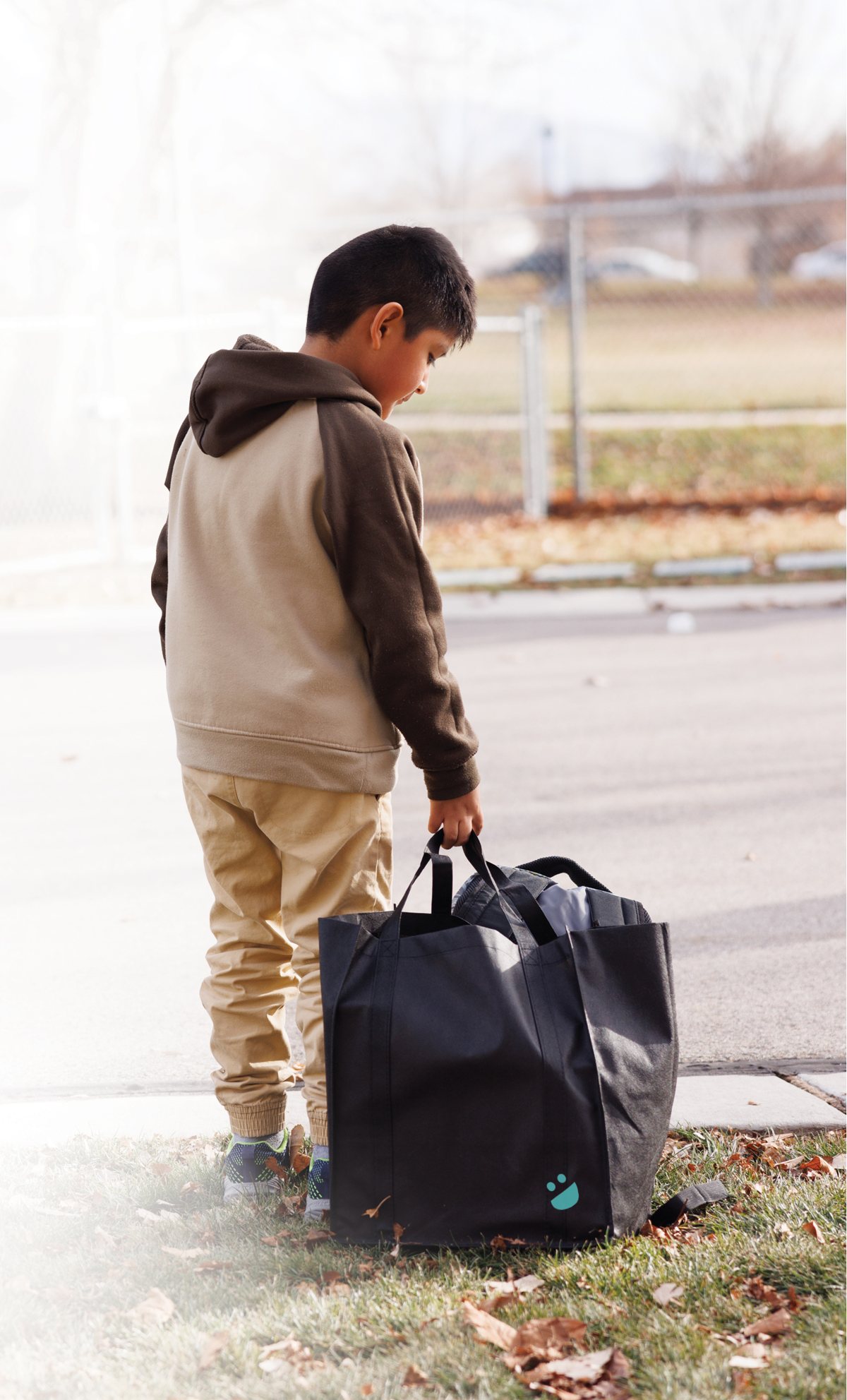 A boy carries a USANA Kids Eat bag on his way home from school